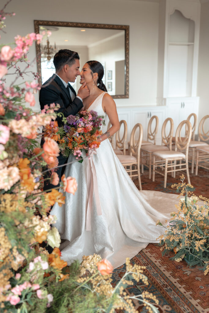 California wedding couple embraces next to floral arch in santa cruz