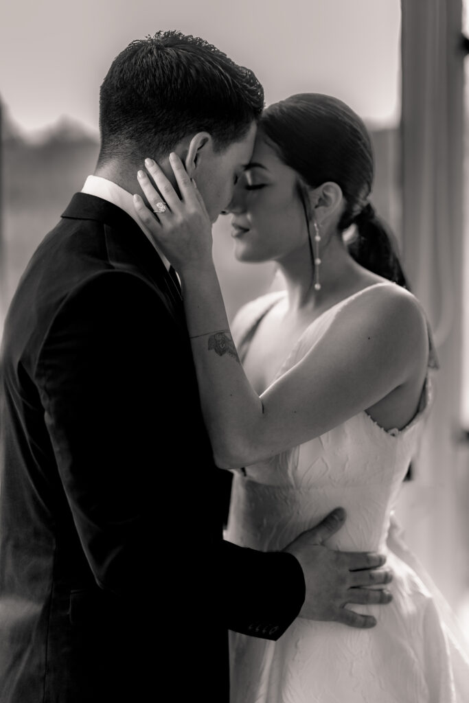 Wedding couple embracing by a window