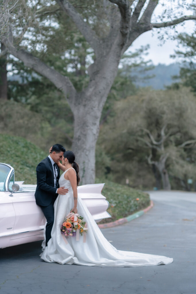 California wedding couple embraces next to getaway car in santa cruz
