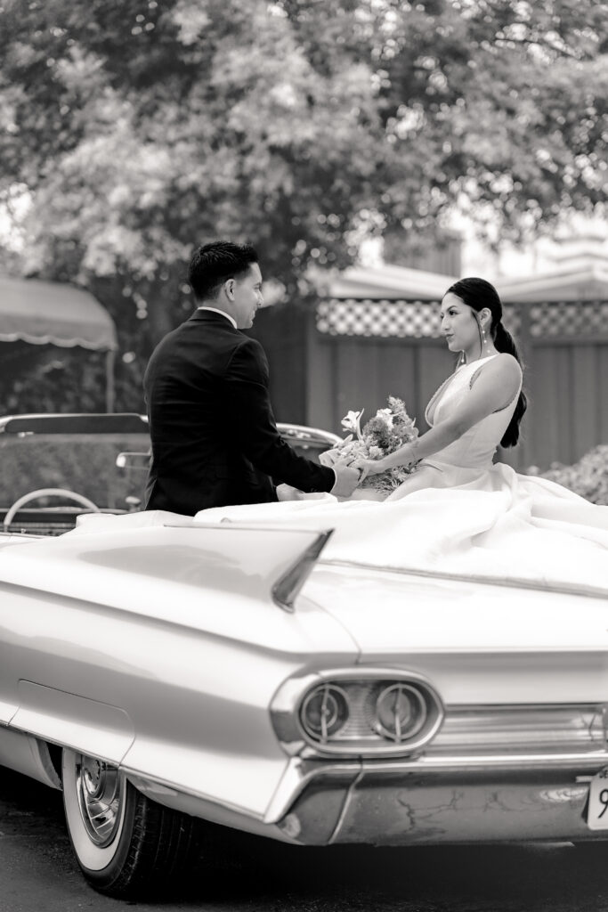 Wedding couple holding hands in getaway car